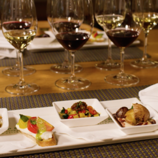 Rectangular plate with four vegetarian wine pairings With wine glasses filled in the background